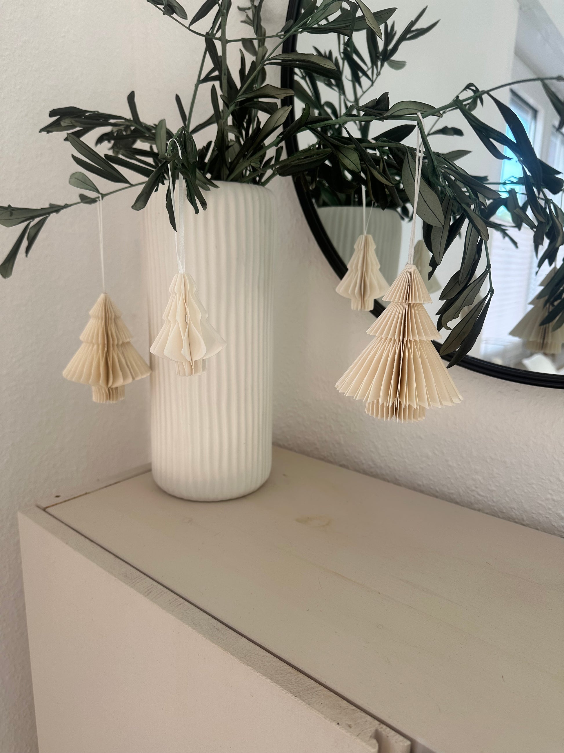 Mehrere weiße Papier-Tannenbäume als moderne Winterdeko