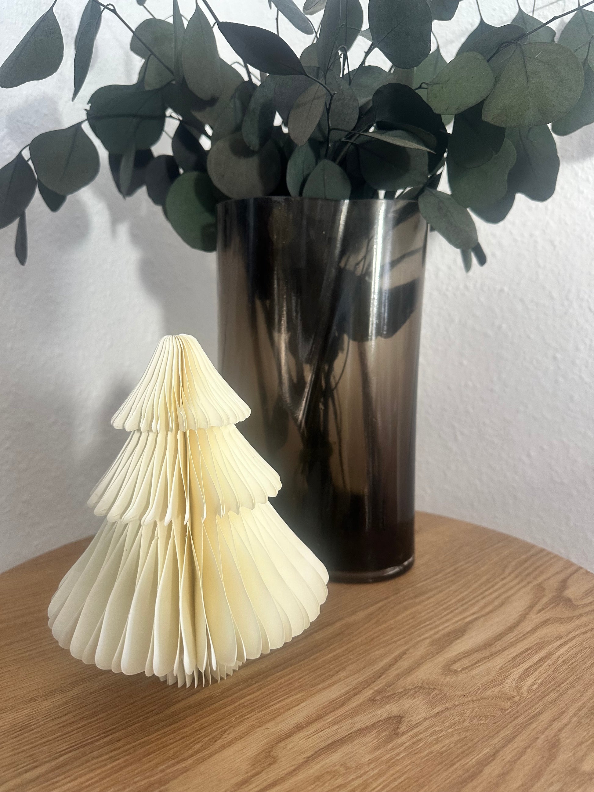 Mehrere Papier-Tannenbäume in verschiedenen Größen als nachhaltige Winterdeko auf Beistelltisch