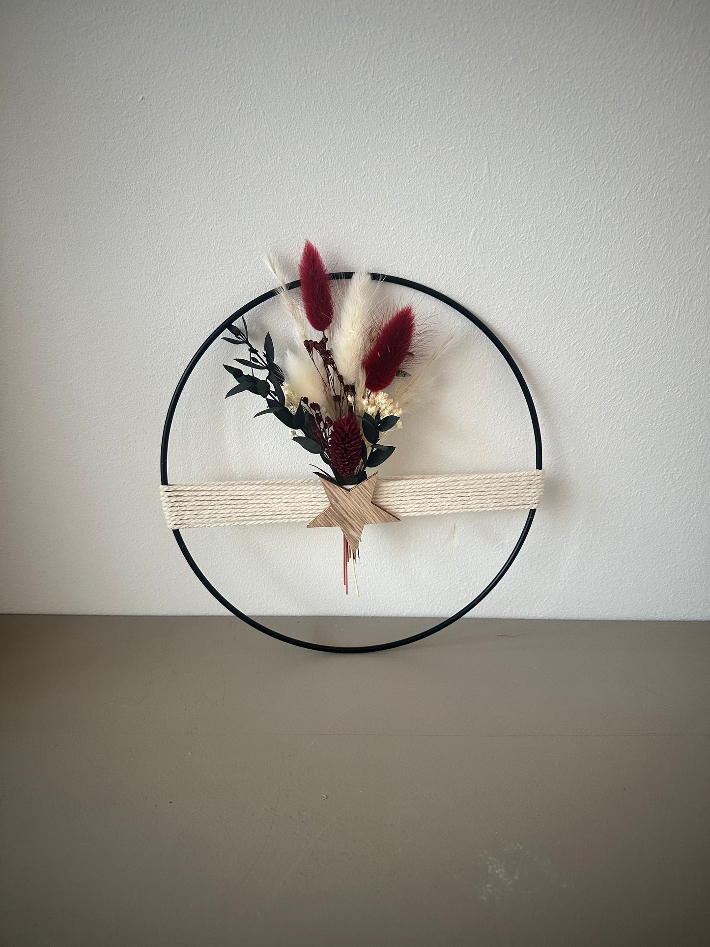 Dekoring mit weihnachtlichem rotem Strauß, Holzstern und Baumwollgarn