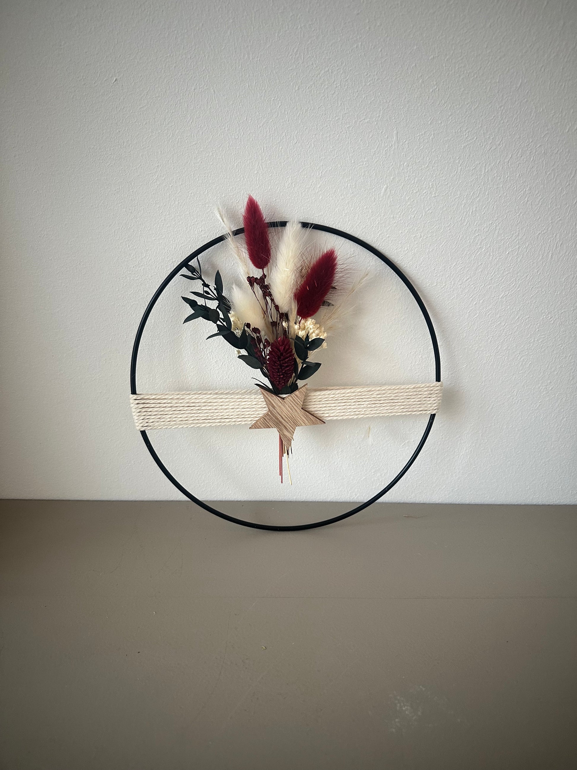 Dekoring mit weihnachtlichem rotem Strauß, Holzstern und Baumwollgarn