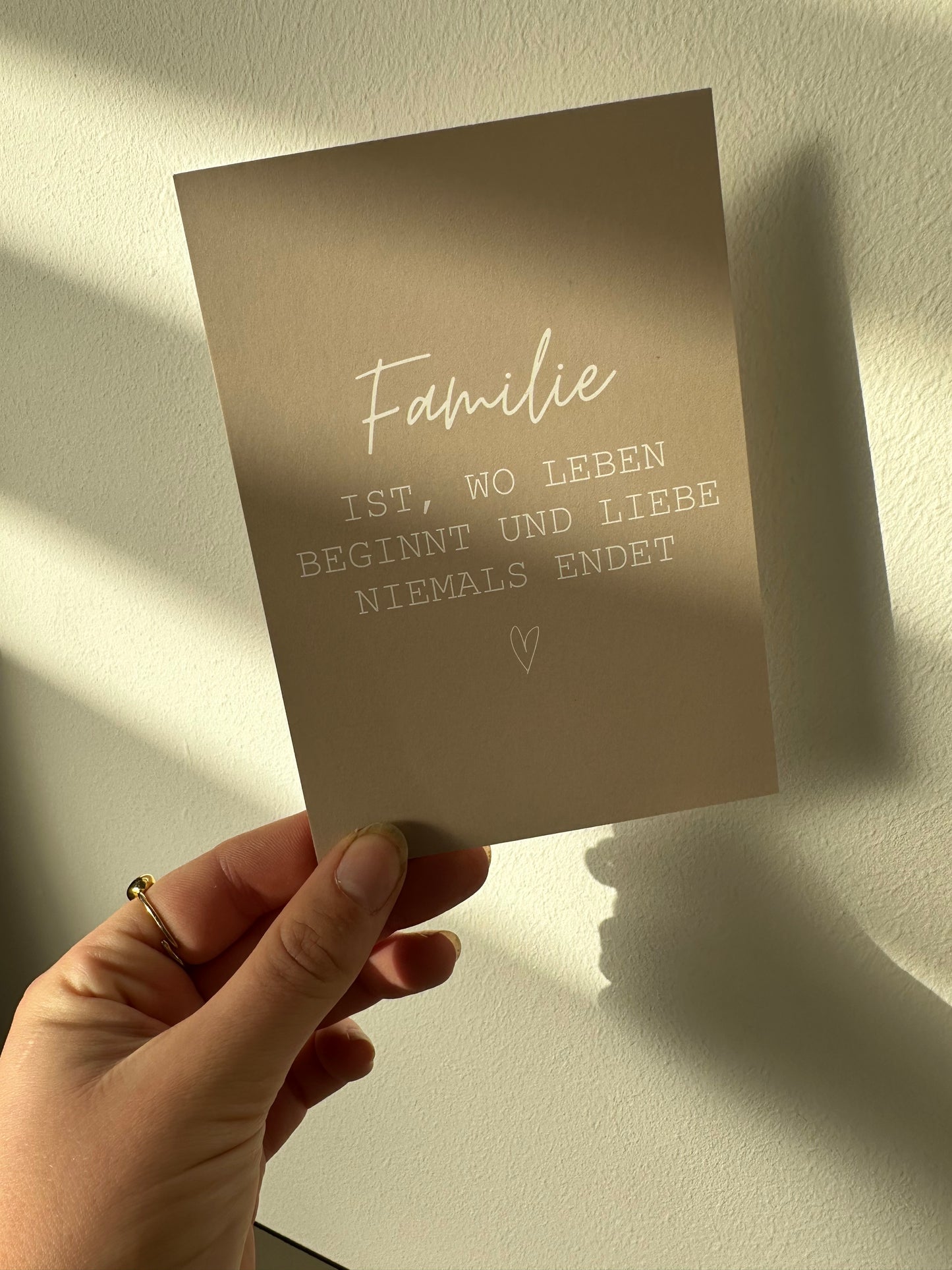 Beige Postkarte mit dem weißen Spruch „Familie ist, wo Leben beginnt und Liebe niemals endet“, liebevoll gestaltet von Lizasliving.